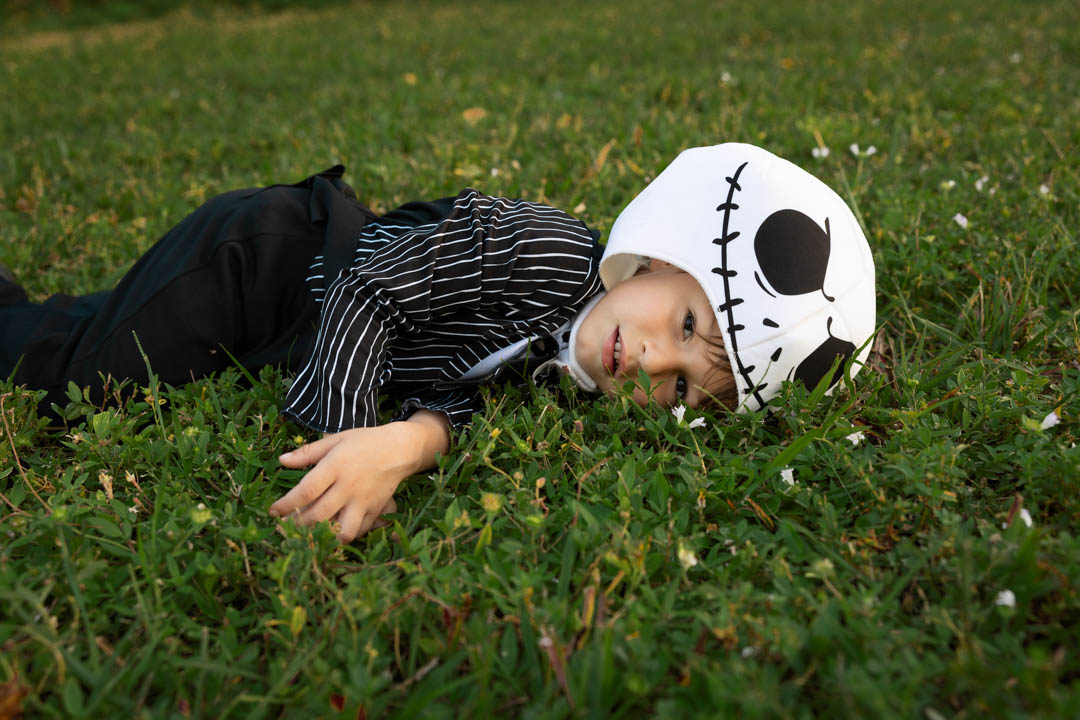 Kid in costume laying in the grass, relaxed